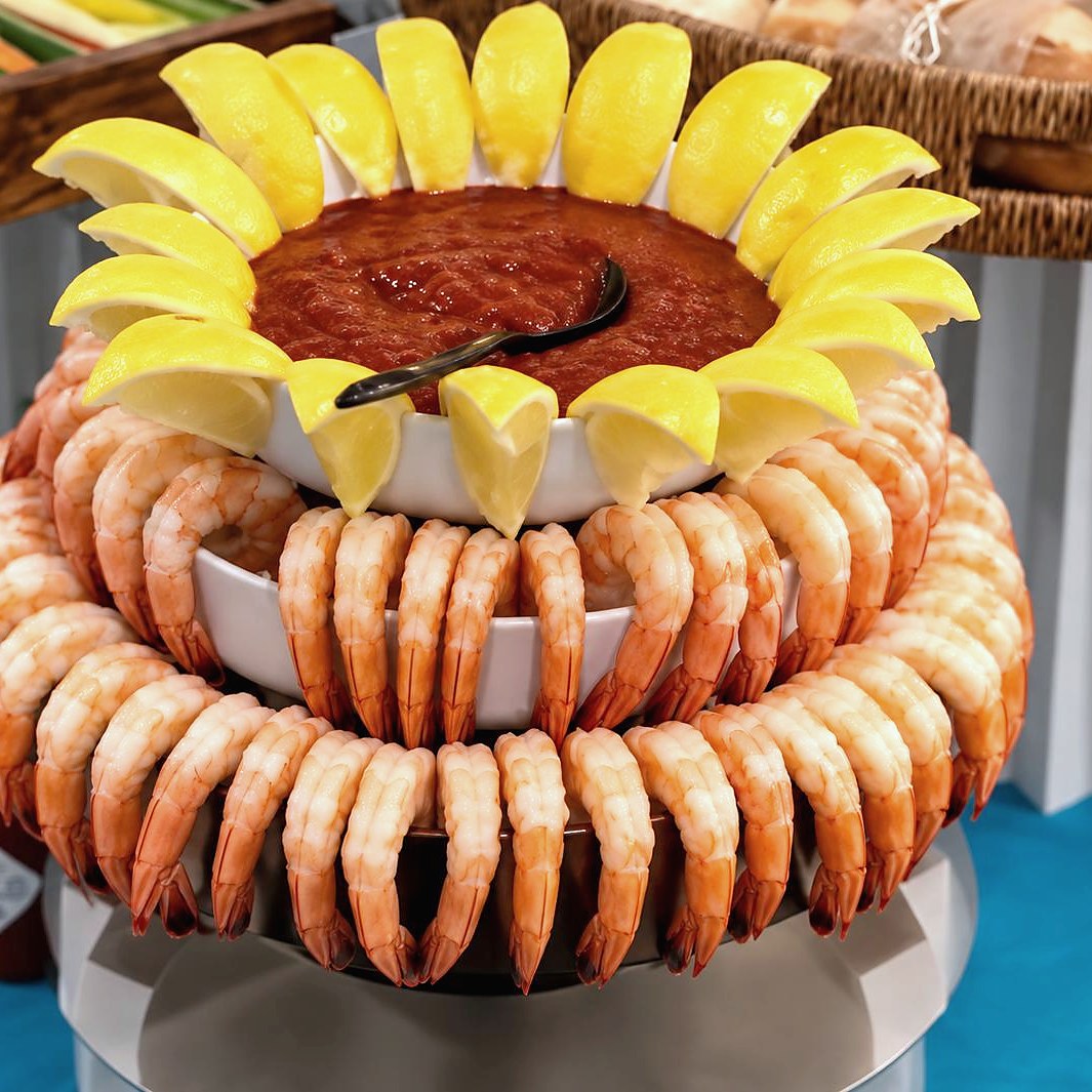 Tiered shrimp cocktail display crowned with cocktail sauce and lemon wedges